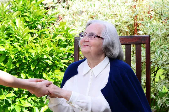 Eine alte Frau sitzt auf einem Holzstuhl von Ostewind Betreuungs- und Entlastungsdienst